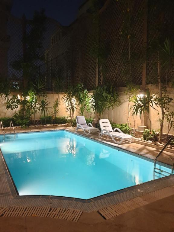 a large swimming pool with two chairs at Heaven new Cairo Villa with Private pool and jacuzzi in Cairo