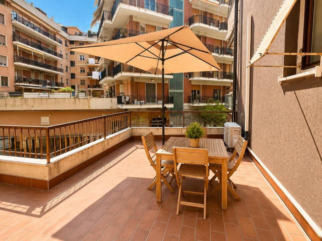 a table and chairs with an umbrella on a balcony at Savona Casa Dolce Vita in Savona