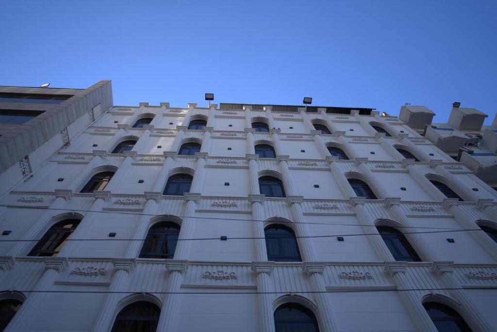 a tall white building with many windows at Consal Hotel 康赛尔酒店 in Baghdād
