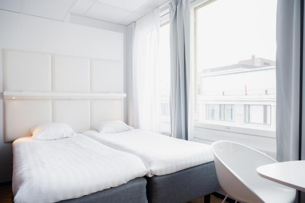 a white bedroom with a bed and a window at Omena Hotel Helsinki Lönnrotinkatu in Helsinki