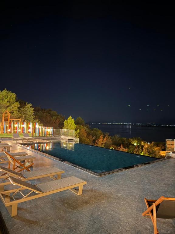 a swimming pool with tables and chairs at night at Lakeside Villas & Jacuzzi Suites in Shirokë