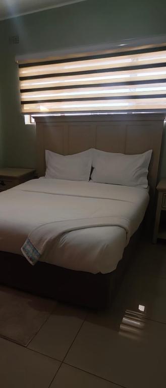 a bed with white pillows in a room with a window at Naomy's Place in Harare