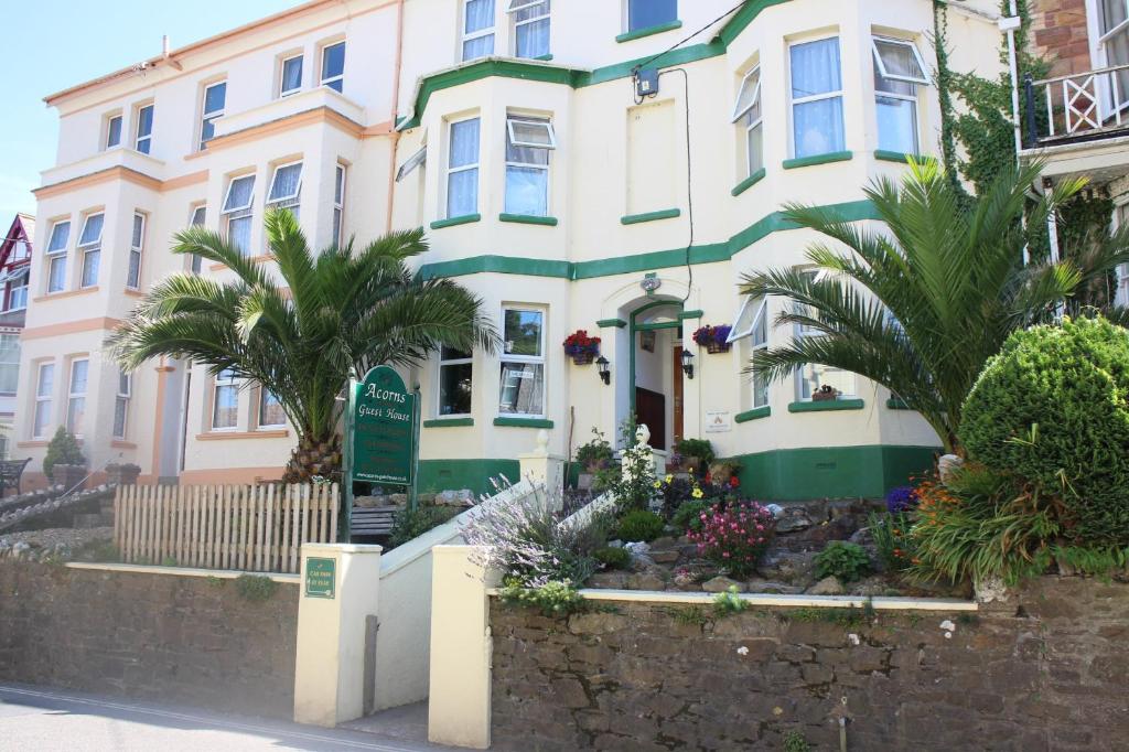 a white and green house with palm trees in front of it at Acorns Guest House in Combe Martin
