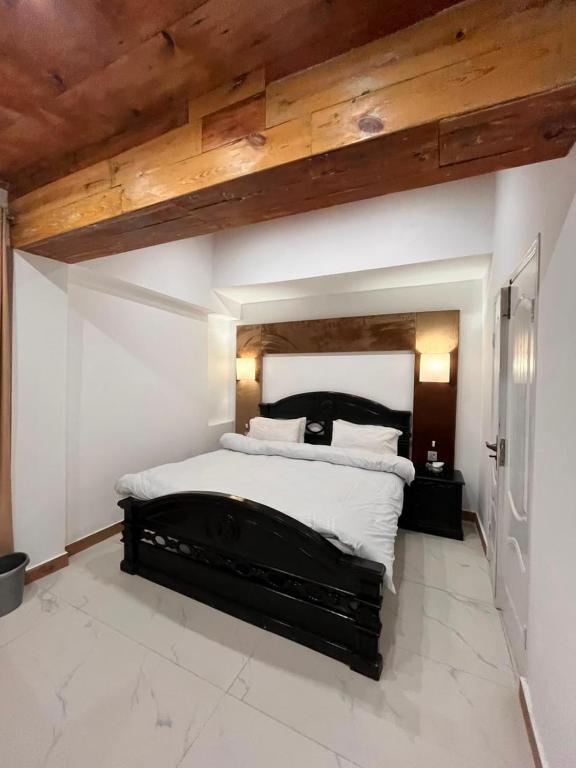 a bedroom with a large bed with a wooden ceiling at Pine Cottage in Murree