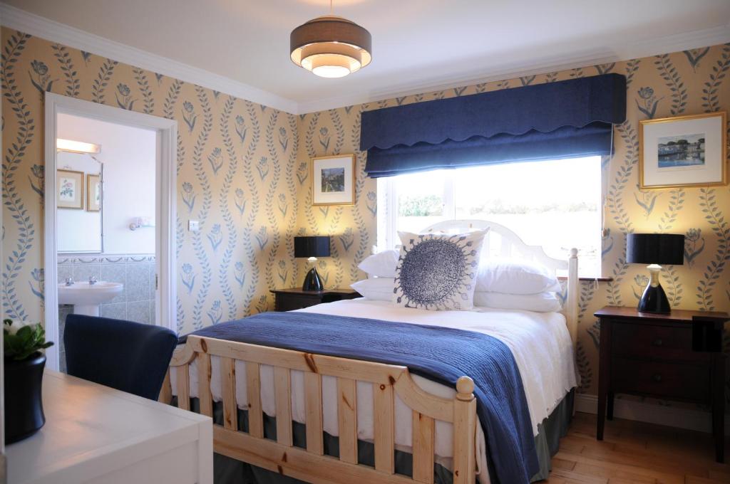 ein Schlafzimmer mit einem Bett mit einer blauen Decke und einem Fenster in der Unterkunft Short Strand Dingle in Dingle