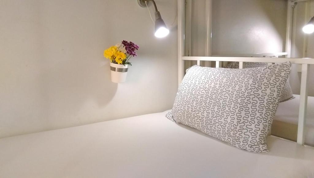 Cama con almohada y maceta de flores en la pared en Salsa Hostel en Chumphon