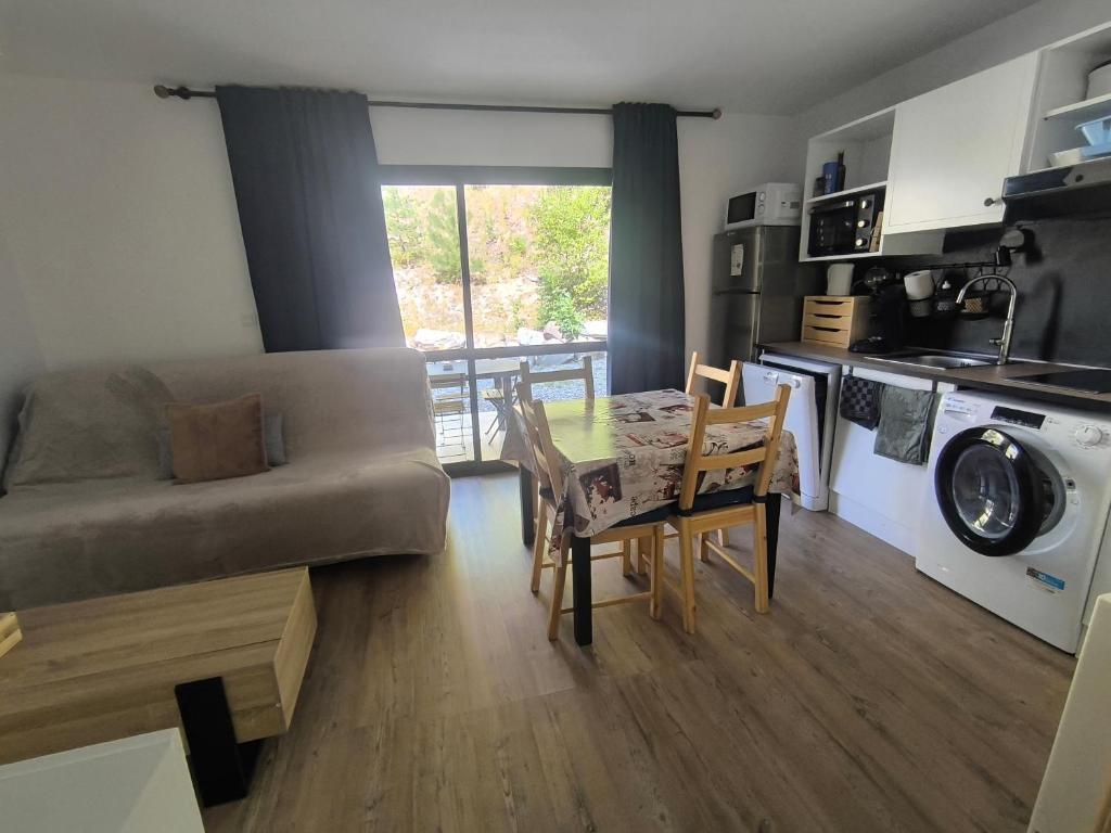 a living room with a couch and a table and chairs at studio tout équipé in Jausiers
