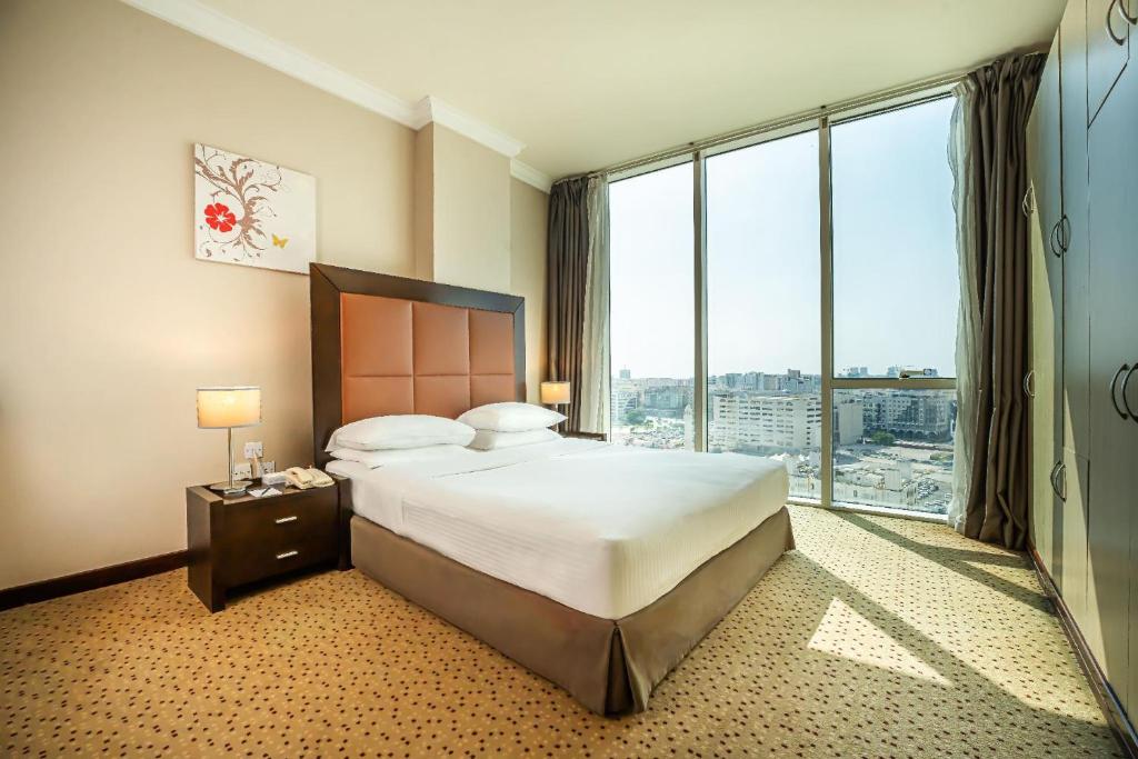 a hotel room with a bed and a large window at Kingsgate Hotel Doha by Millennium Hotels in Doha