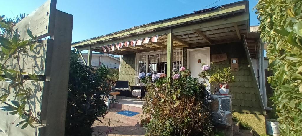 a house with a porch with flowers on it at Cabaña Los Corsarios in El Quisco