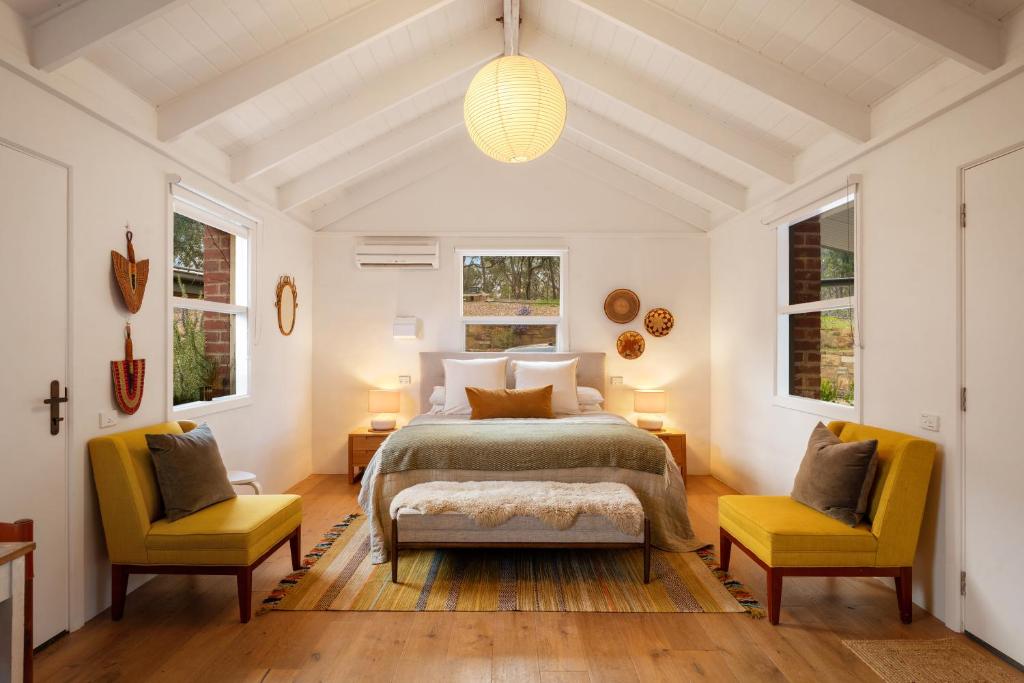 a bedroom with a bed and two yellow chairs at HeartStone Hill - Studio in Castlemaine