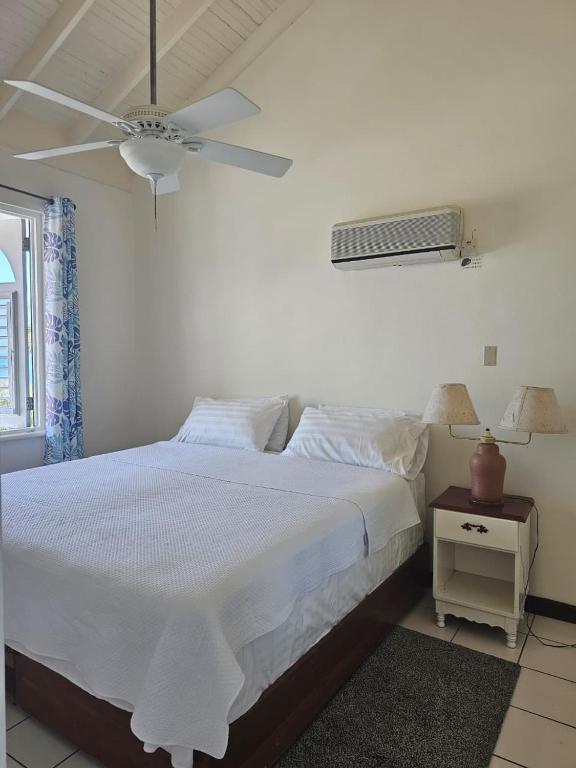 a bedroom with a white bed and a ceiling fan at A World Away in Montego Bay