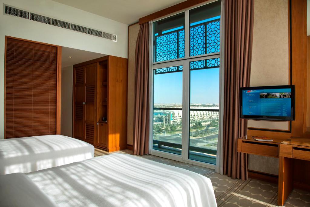 a bedroom with a bed and a tv and a large window at Yas Island Rotana Abu Dhabi in Abu Dhabi
