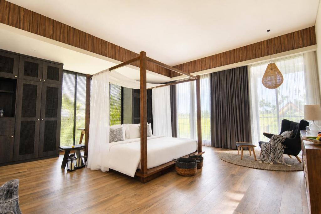 a bedroom with a canopy bed and a living room at Umah Tirta Estate in Ubud