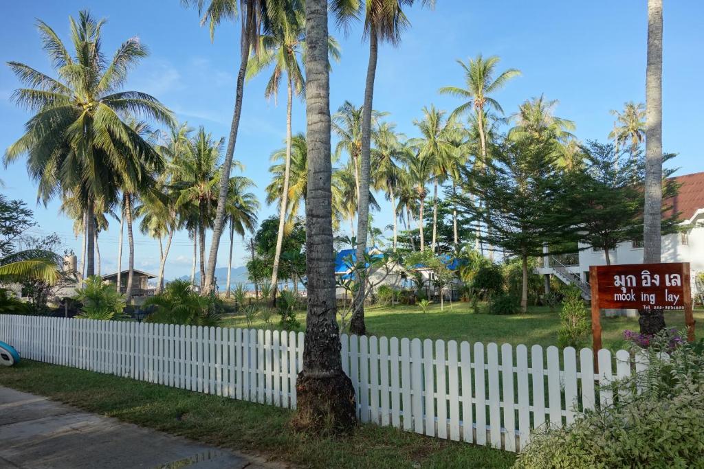 a white picket fence with palm trees and a sign at Mook Ing Lay in Ko Mook