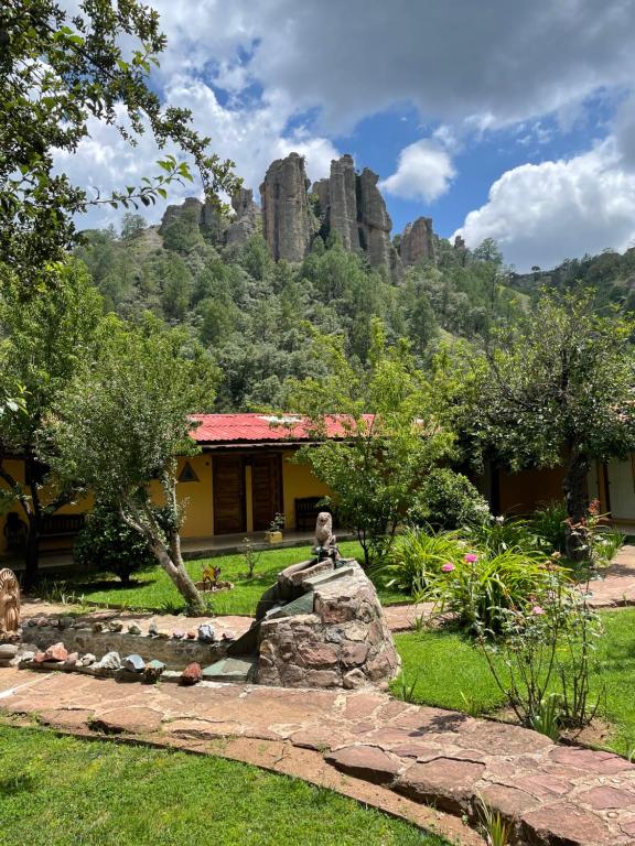 a garden with a house and a mountain in the background at Hotel Paraiso del Oso in Cerocahui