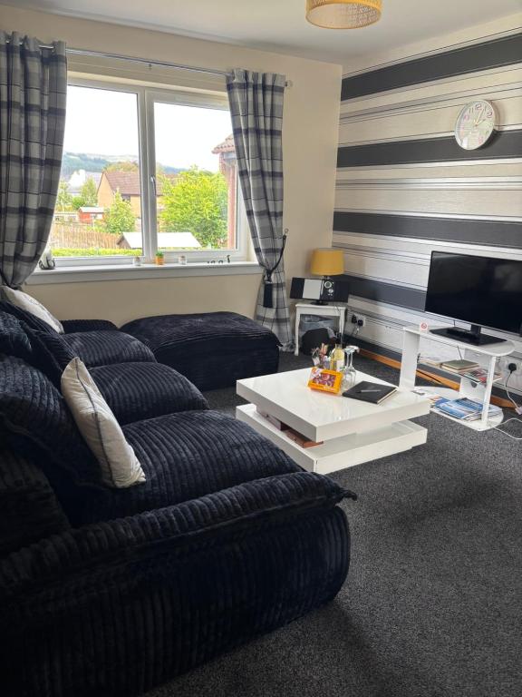 a living room with a couch and a tv at Cameron apartment Loch Ness in Fort Augustus