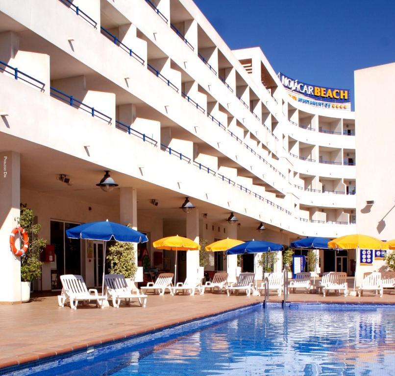 una piscina de hotel con sillas y sombrillas en Hotel Apartamentos Mojácar Beach, en Mojácar