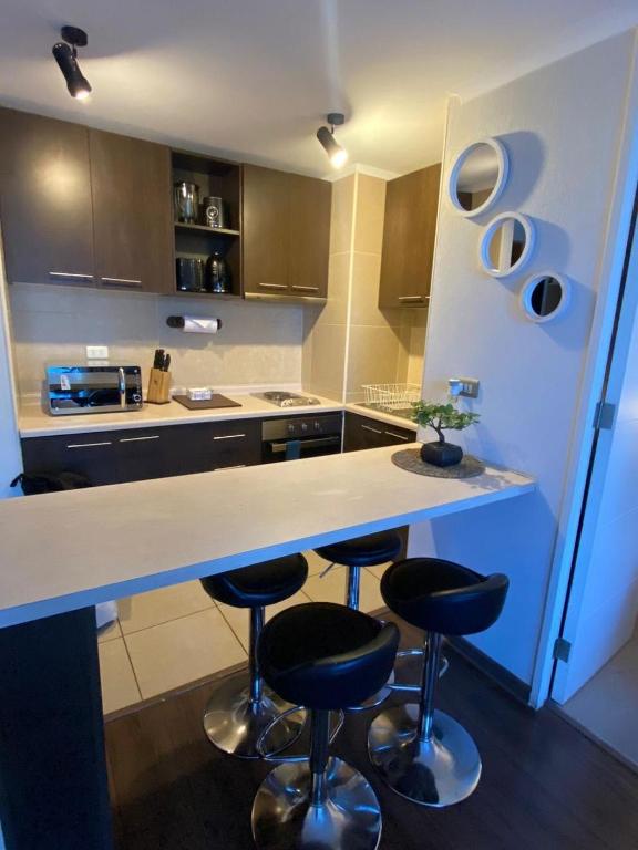 a kitchen with two bar stools and a counter at Hermoso depto. con estacionamiento in Los Ángeles
