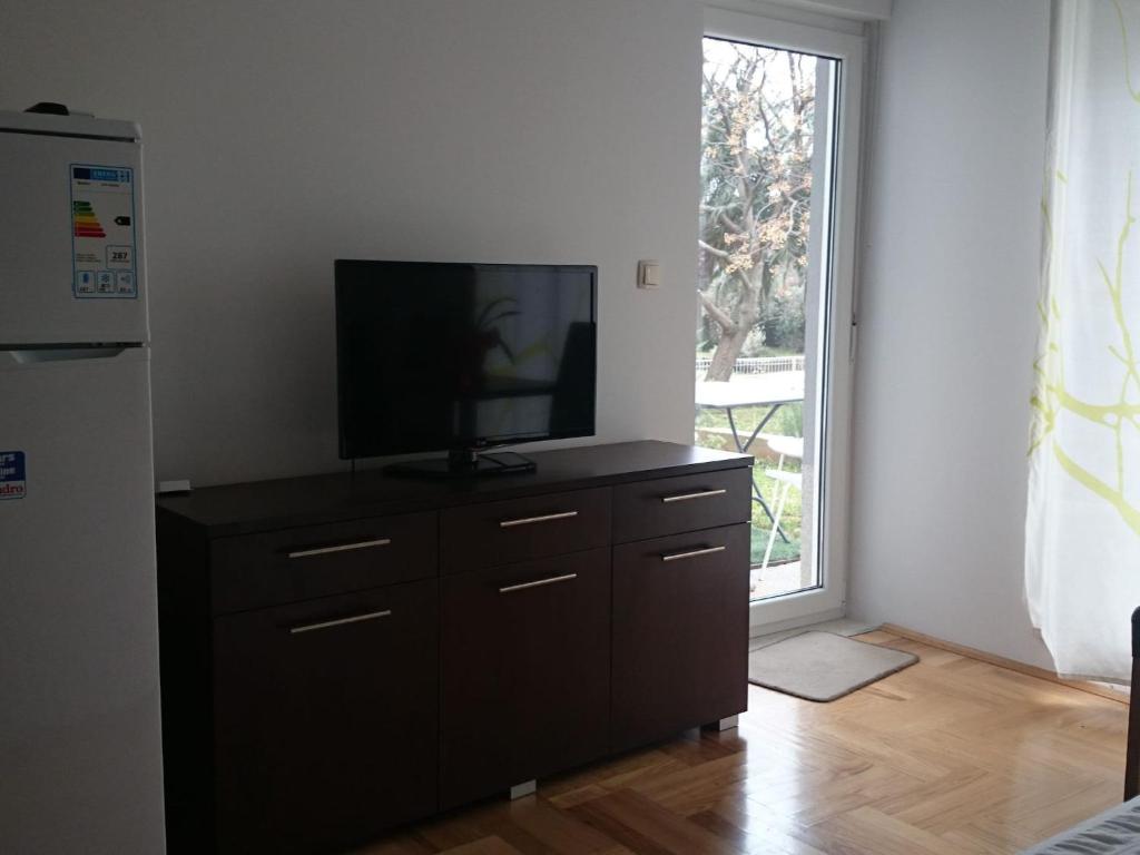 a television on a dresser in a room with a window at Apartments Despot Zaostrog RO in Zaostrog