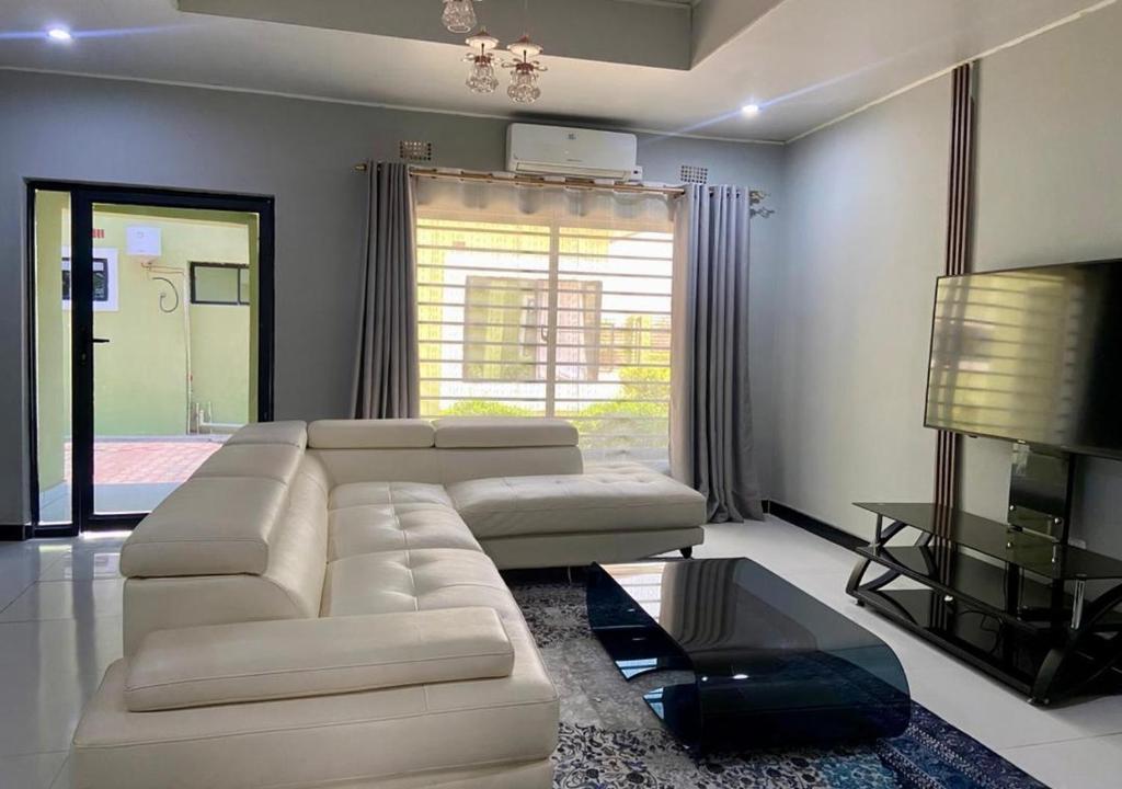 a living room with a white couch and a television at Pizzaro Flats in Lusaka