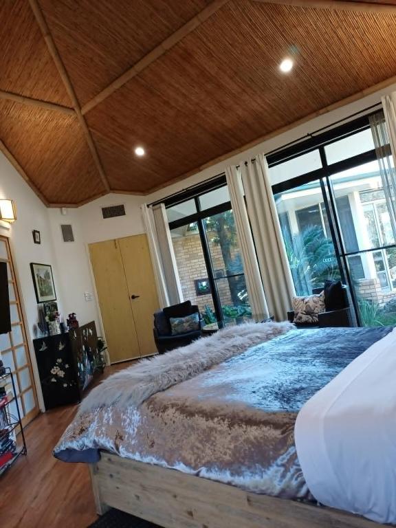 a bedroom with a large bed and large windows at Garden Suite, self contained, Hunter Valley in Muswellbrook