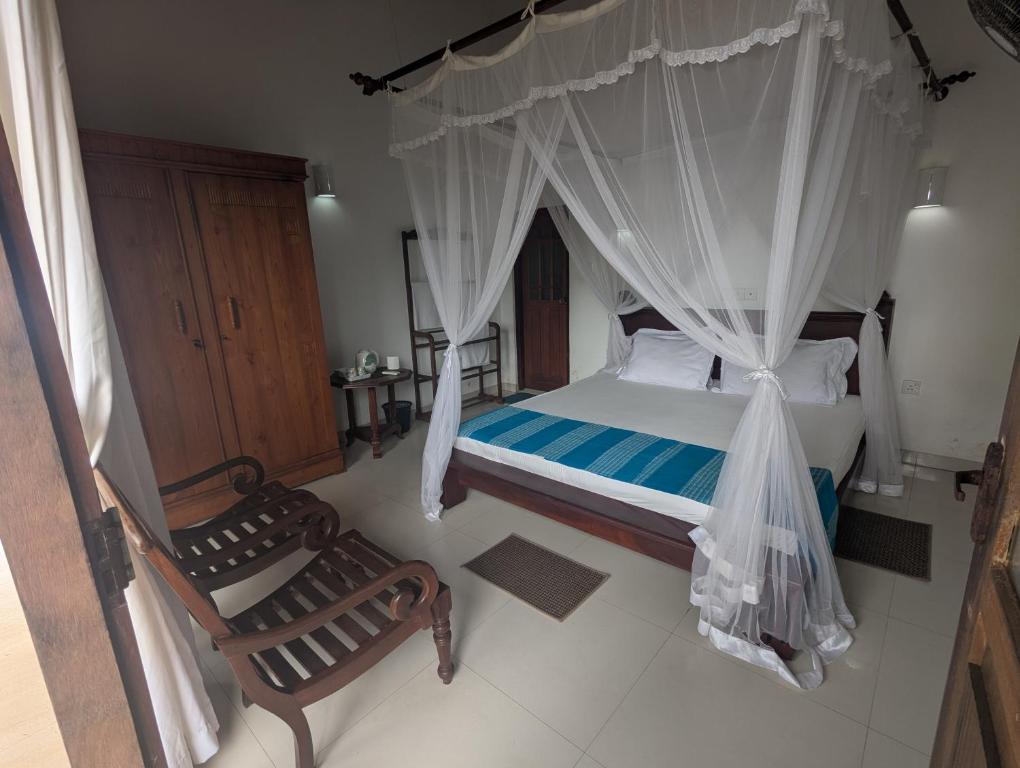 a bedroom with a canopy bed and two chairs at Ocean Haven in Induruwa