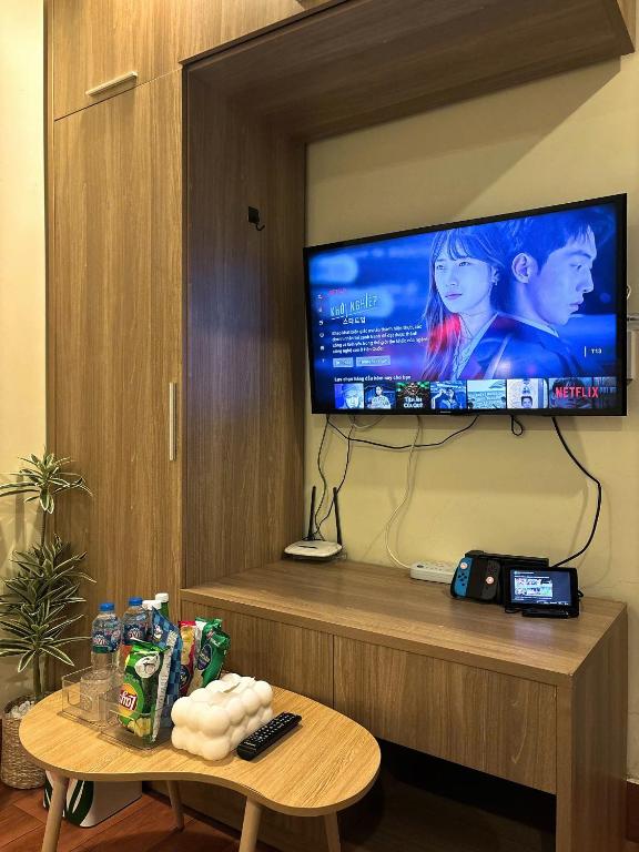 a television on a wall with a table in a room at Flick Zone Trung Lực in Lực Hánh