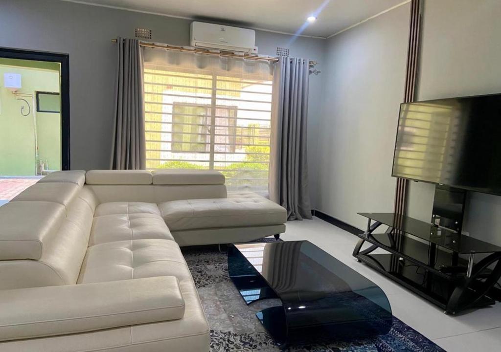 a living room with a white couch and a television at Pizzaro Flats 2 in Chongwe