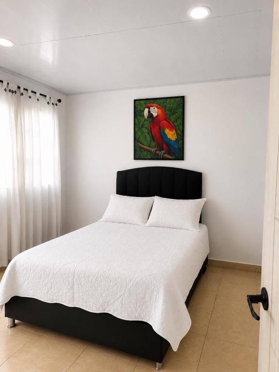 a bedroom with a bed with a parrot painting on the wall at Finca Cabañas el Higueron in Nocaima
