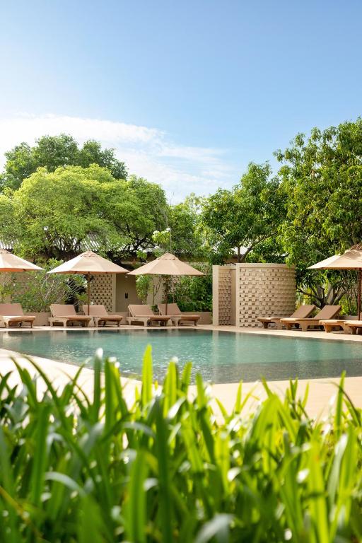a swimming pool with chairs and umbrellas at Hidden Secrets Dambulla in Dambulla