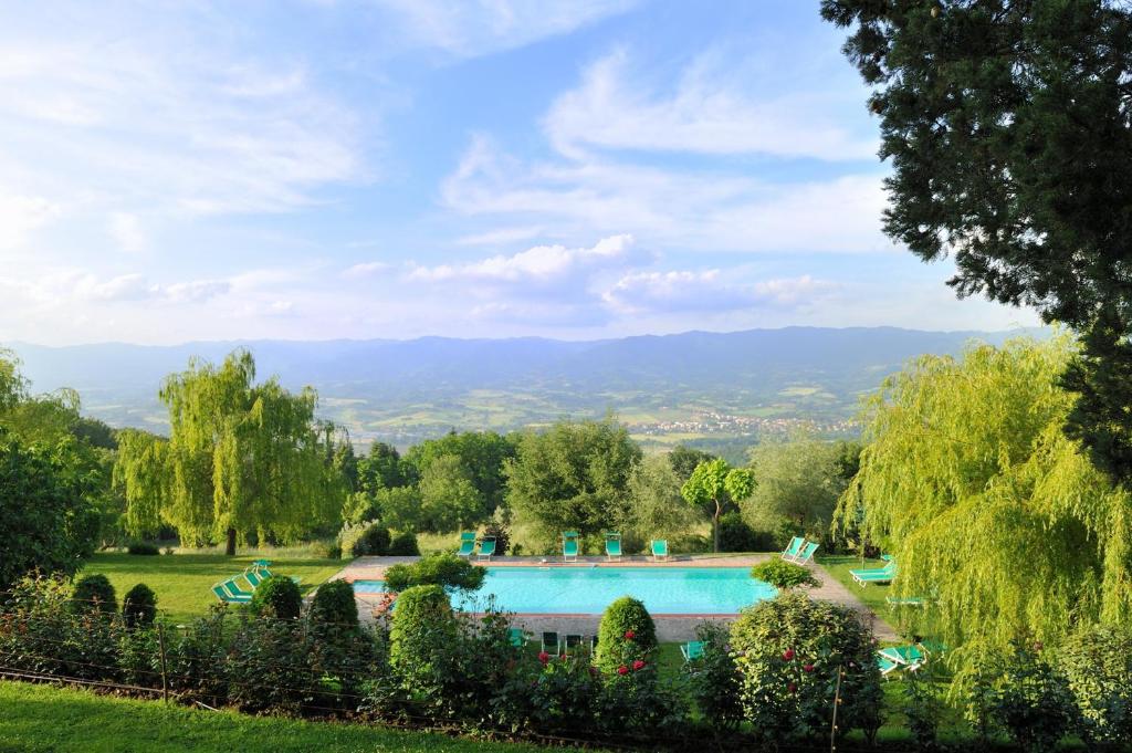 a swimming pool in a garden with trees and mountains at Villa Campestri Olive Oil Resort in Vicchio