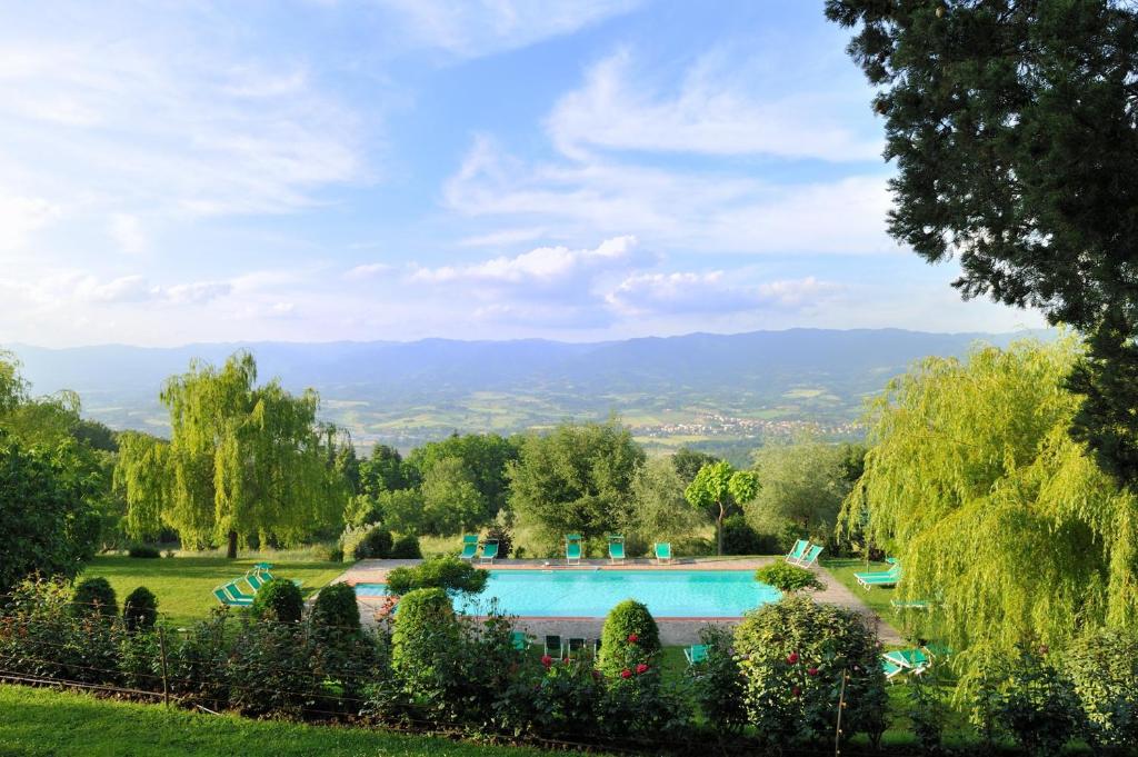 una piscina in un giardino con alberi e montagne di Villa Campestri Olive Oil Resort a Vicchio