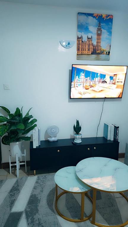 a living room with two tables and a picture on the wall at Kerry Luxury Stays in Athi River
