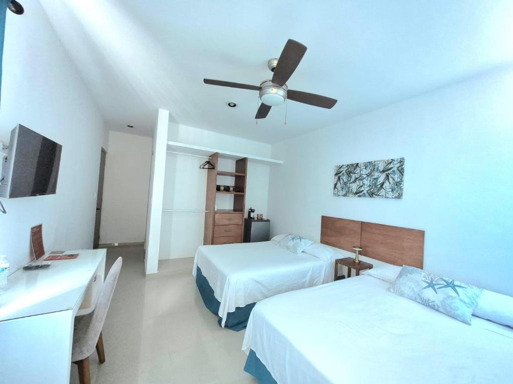a hotel room with two beds and a ceiling fan at Casa Terracota Micro Hotel Consulado in Mérida