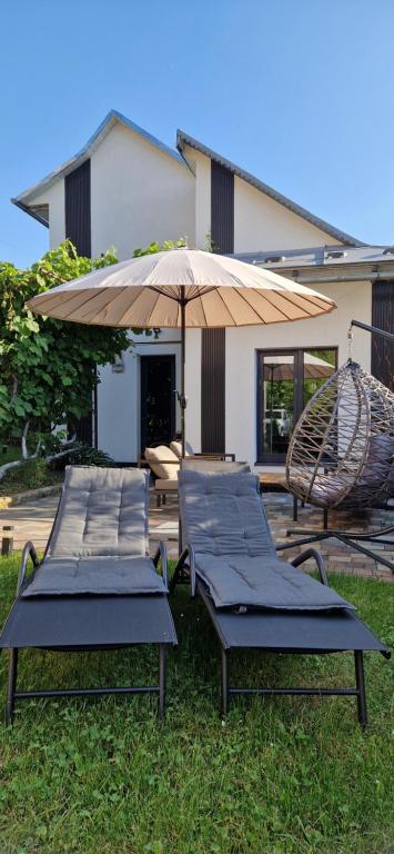 two lounge chairs and an umbrella and a swing at Котедж Gudz in Yaremche