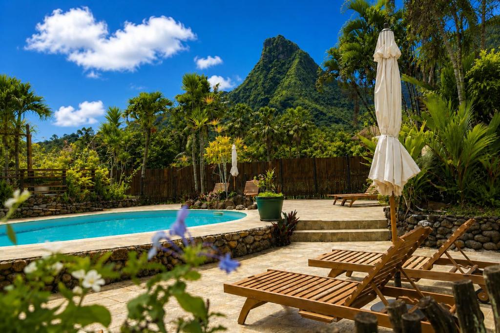 a patio with a pool and a umbrella and benches at Eco Lodge Village Temanoha in Paopao