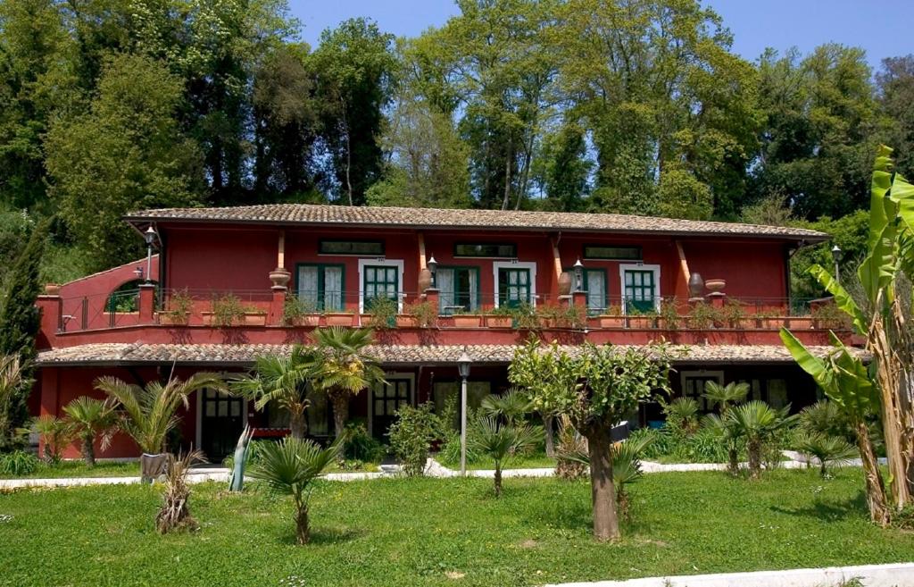 ein rotes Haus mit einem Balkon auf einem Hof in der Unterkunft Veio Residence Resort in La Giustiniana