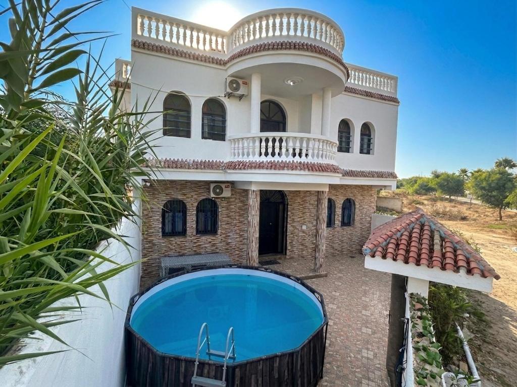 a house with a swimming pool in front of it at Villa TAHA piscine jacuzzi clim in Martil