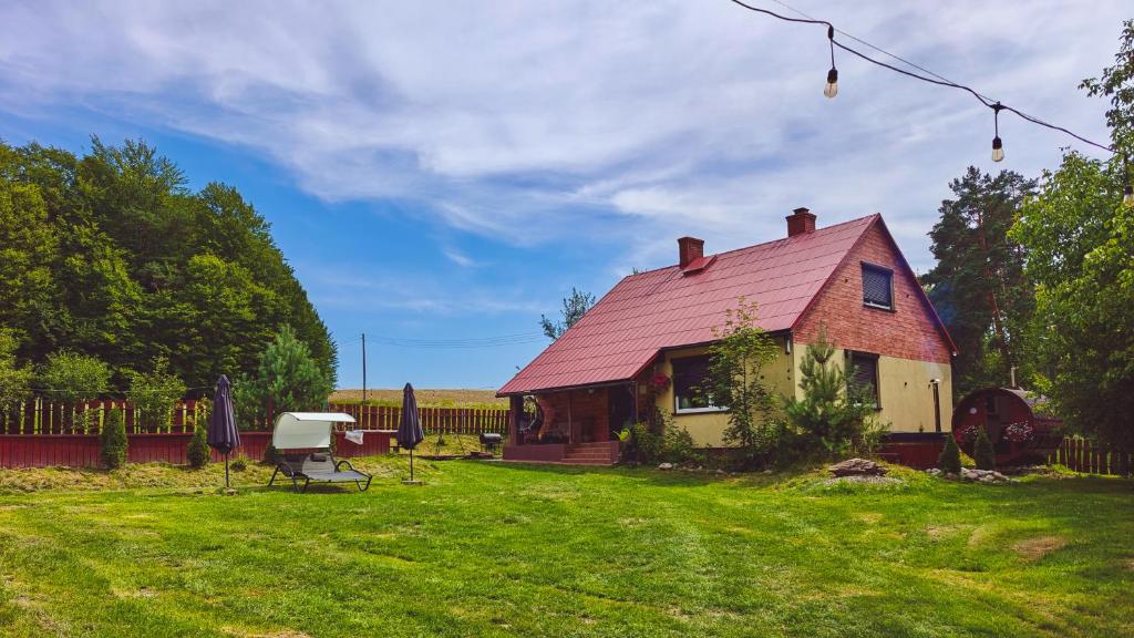 a house with a red roof in a yard at Gajówka na Roztoczu in Lubycza Królewska