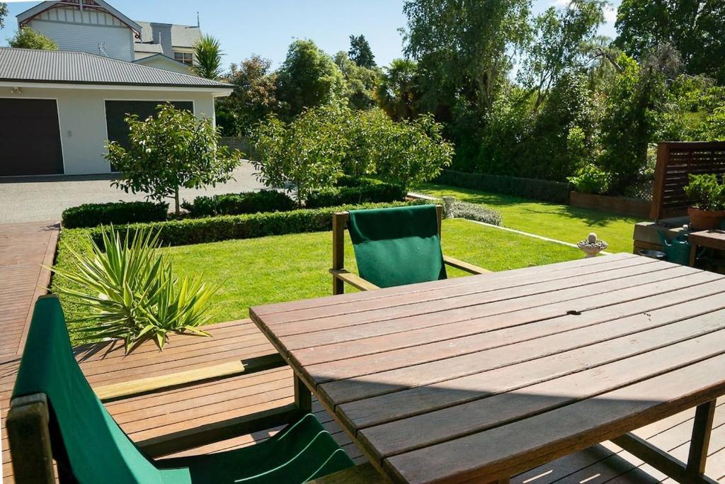 a wooden table and two green chairs in a yard at Brougham Street B and B in Nelson