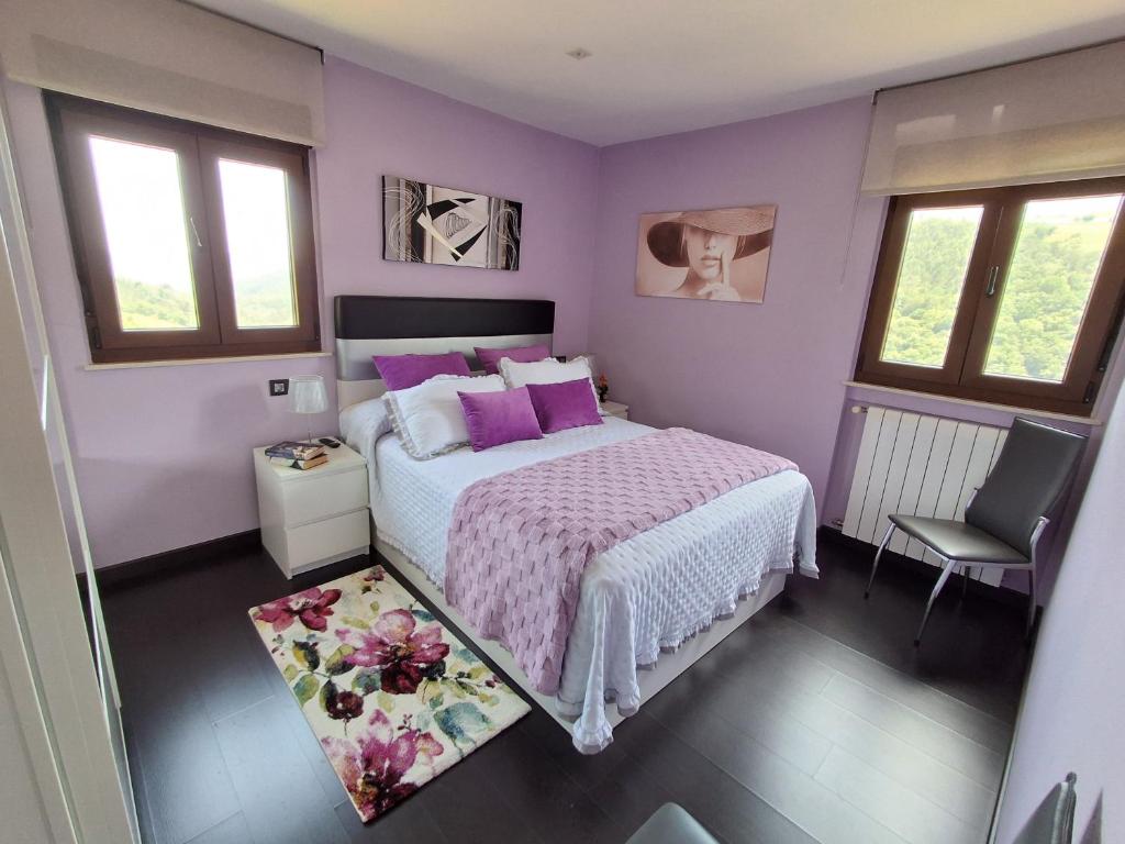 ein lila Schlafzimmer mit einem Bett und einem Stuhl in der Unterkunft Casa Pasarón in Luarca