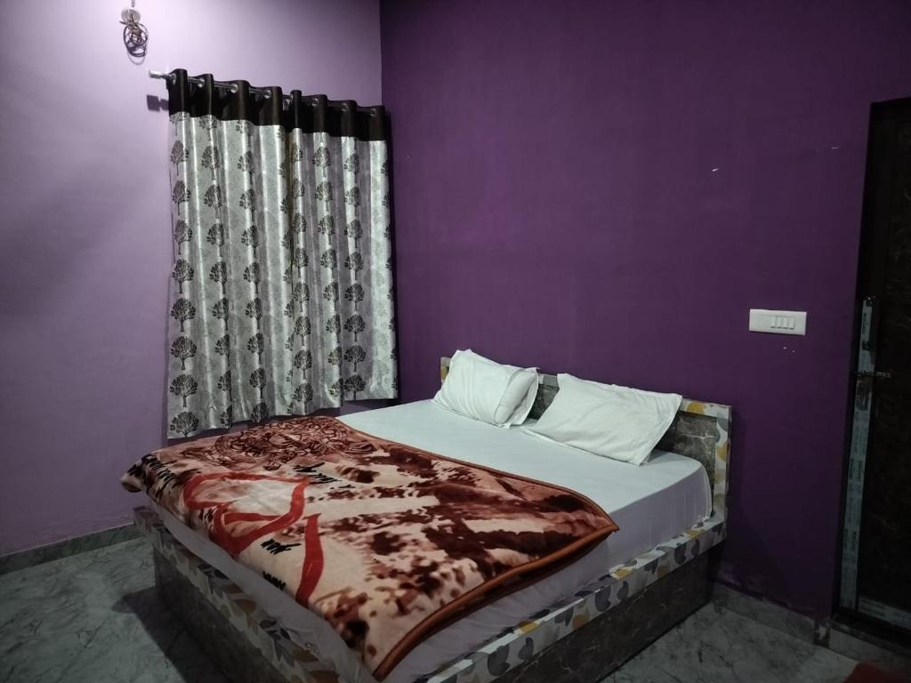 a bed in a room with a purple wall at Hotel Shyam Vandan in Rīngas