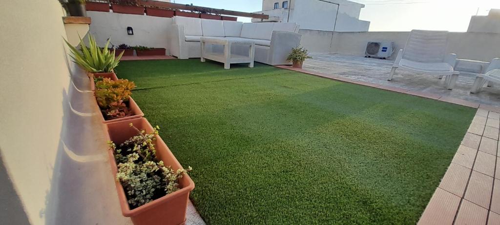 a patio with green grass and plants on a building at Ramzam - Spacious & Modern 3 bedroom apartment with roof terrace in Marsaskala