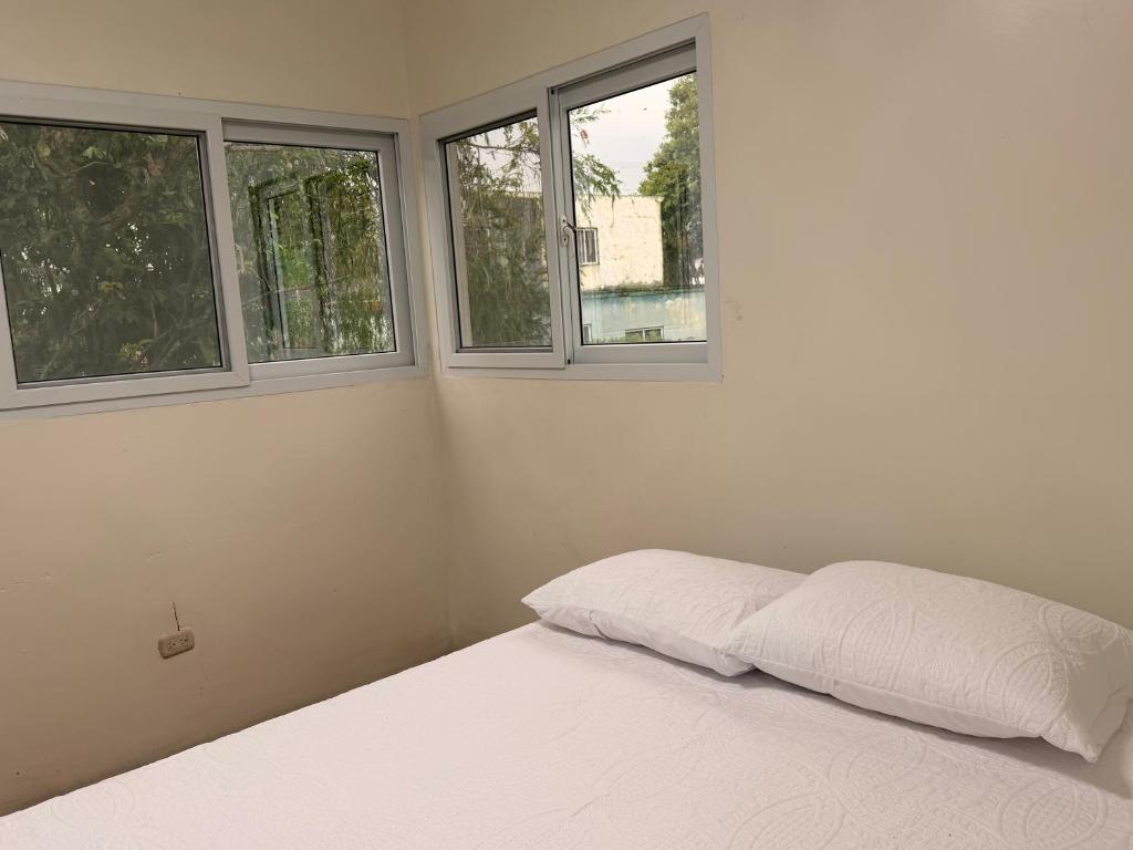 a white bedroom with two windows and a bed at Dormilón in San Felipe