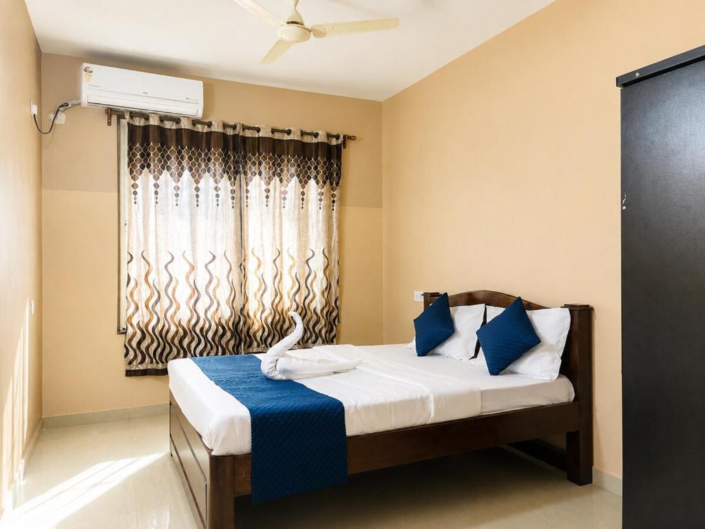 a bedroom with a bed with blue pillows and a window at Casafern Homestay Goa in Varca