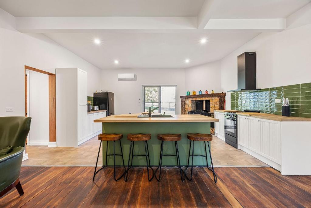 a kitchen with a green island with stools at Jam Cottage Tolmie in Tolmie