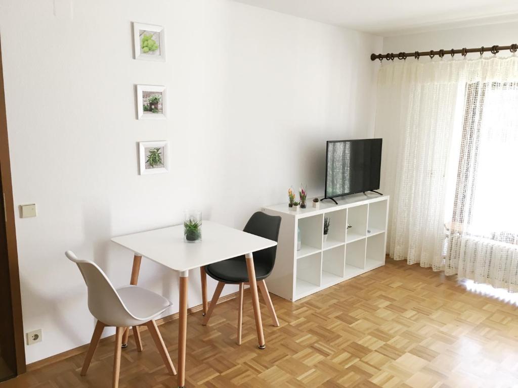 a living room with a table and chairs and a television at Weststadt Apartment in Baden-Baden