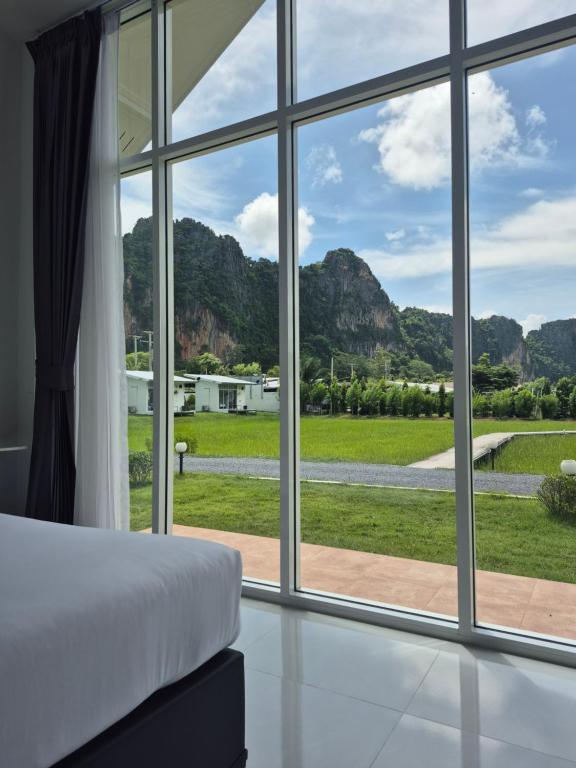 a bedroom with a large window looking out at a yard at นัชชานามุงโฮมสเตย์ in Ban Mung