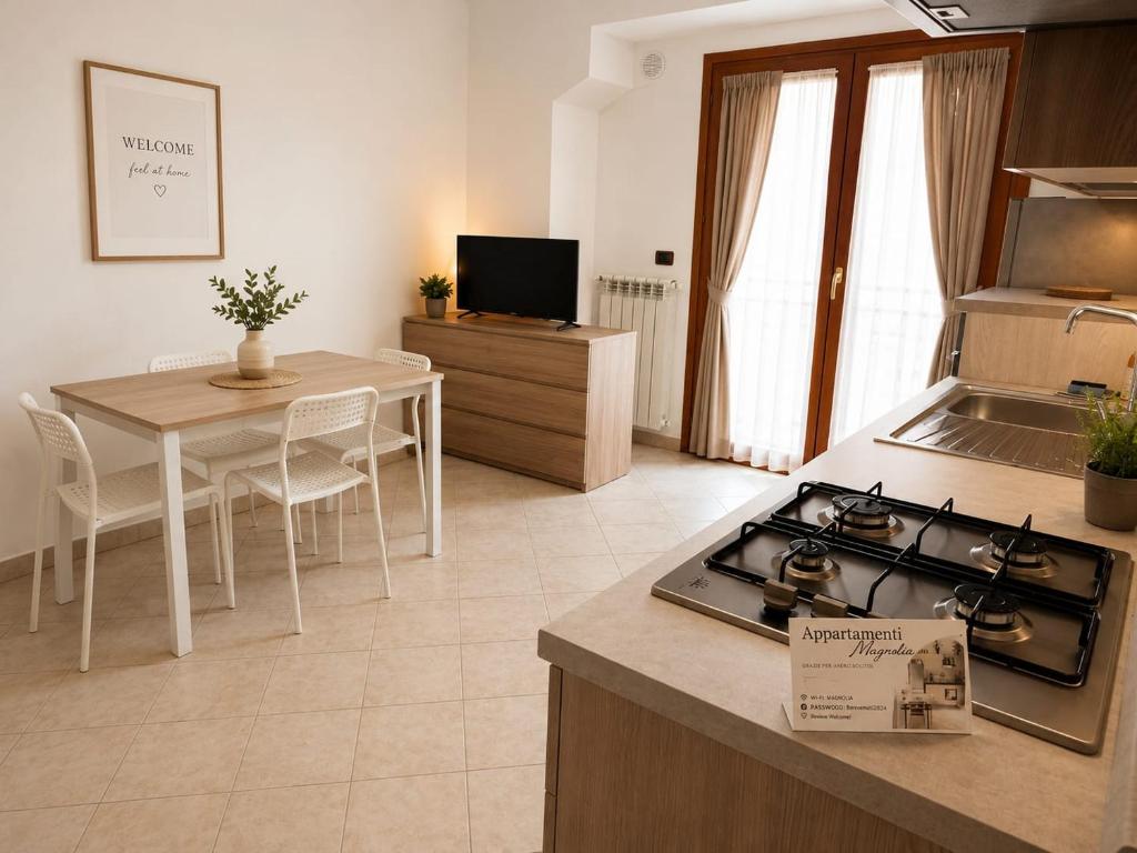 a kitchen and dining room with a stove and a table at Appartamento Magnolia 209 in Pomezia