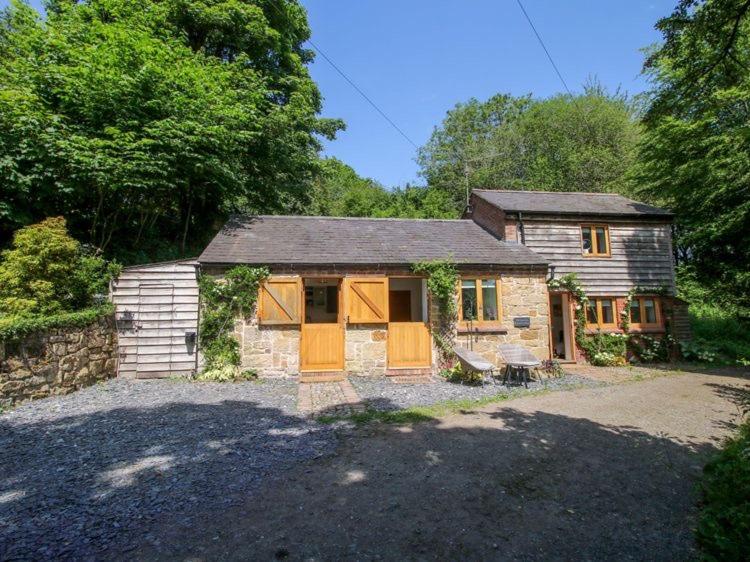 a stone house with orange doors in a yard at Woodland, Canal & Lakeside Cottage in Ellesmere